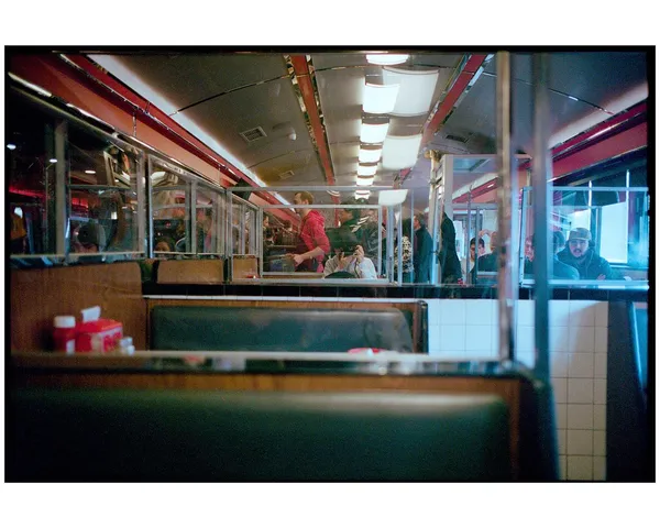 A self-portrait reflected in the windows of a red-trimmed diner.