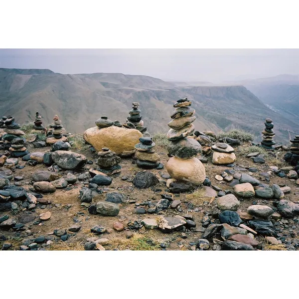 Rock cairns gathered against a distant mountain landscape.