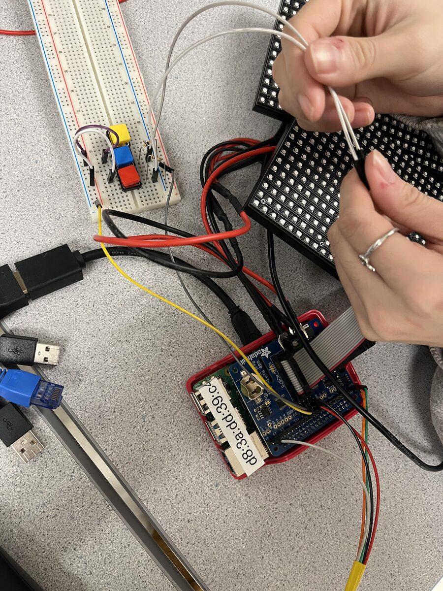 A Raspberry Pi, LED matrix driver, buttons, wiring, and an RGB panel being assembled on a lab bench.