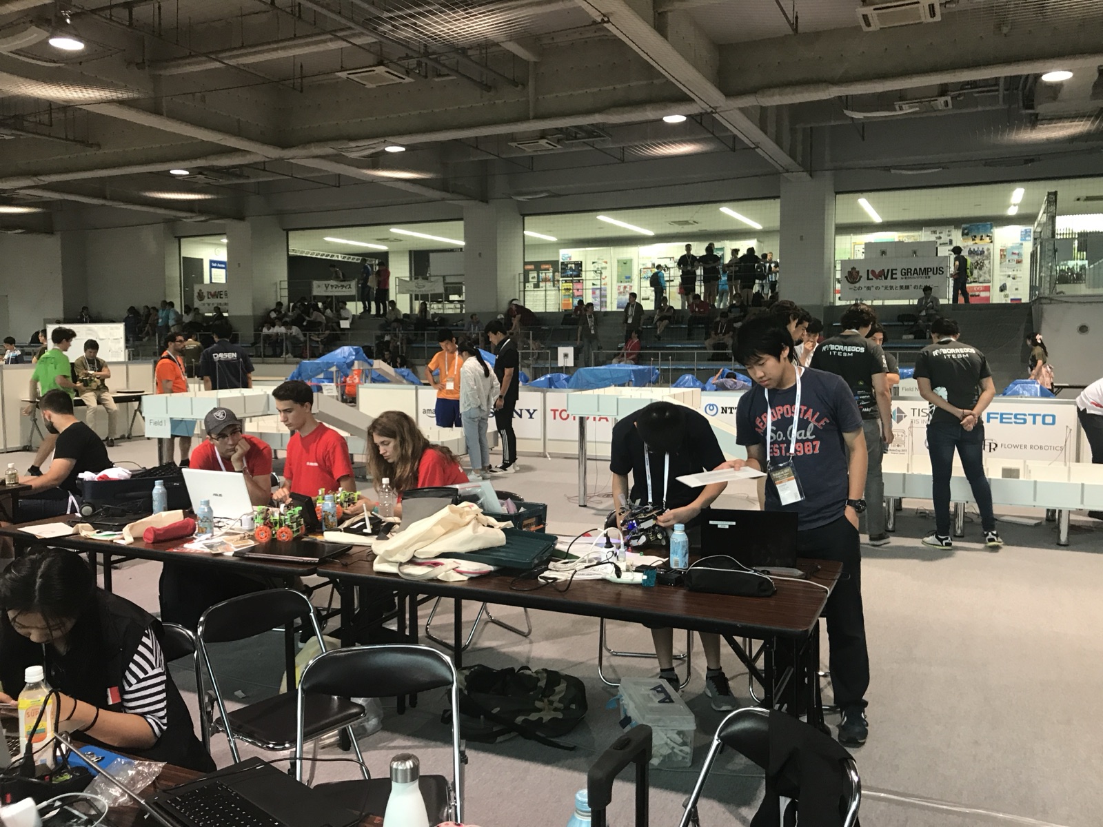 Teams preparing and testing their robots beside the competition fields at the 2017 international final in Japan.